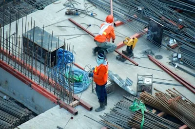 Operários TEENUS em canteiro de obra com ferragens expostas